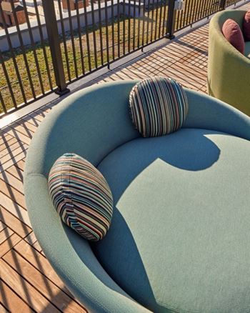 A blue couch with striped pillows on a wooden deck.